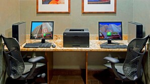 A workspace with two desktop computers, two printers, two keyboards, two mice, and two office chairs.