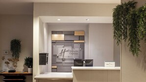 A reception desk with a Holiday Inn Express sign, a digital thermostat, and a plant.