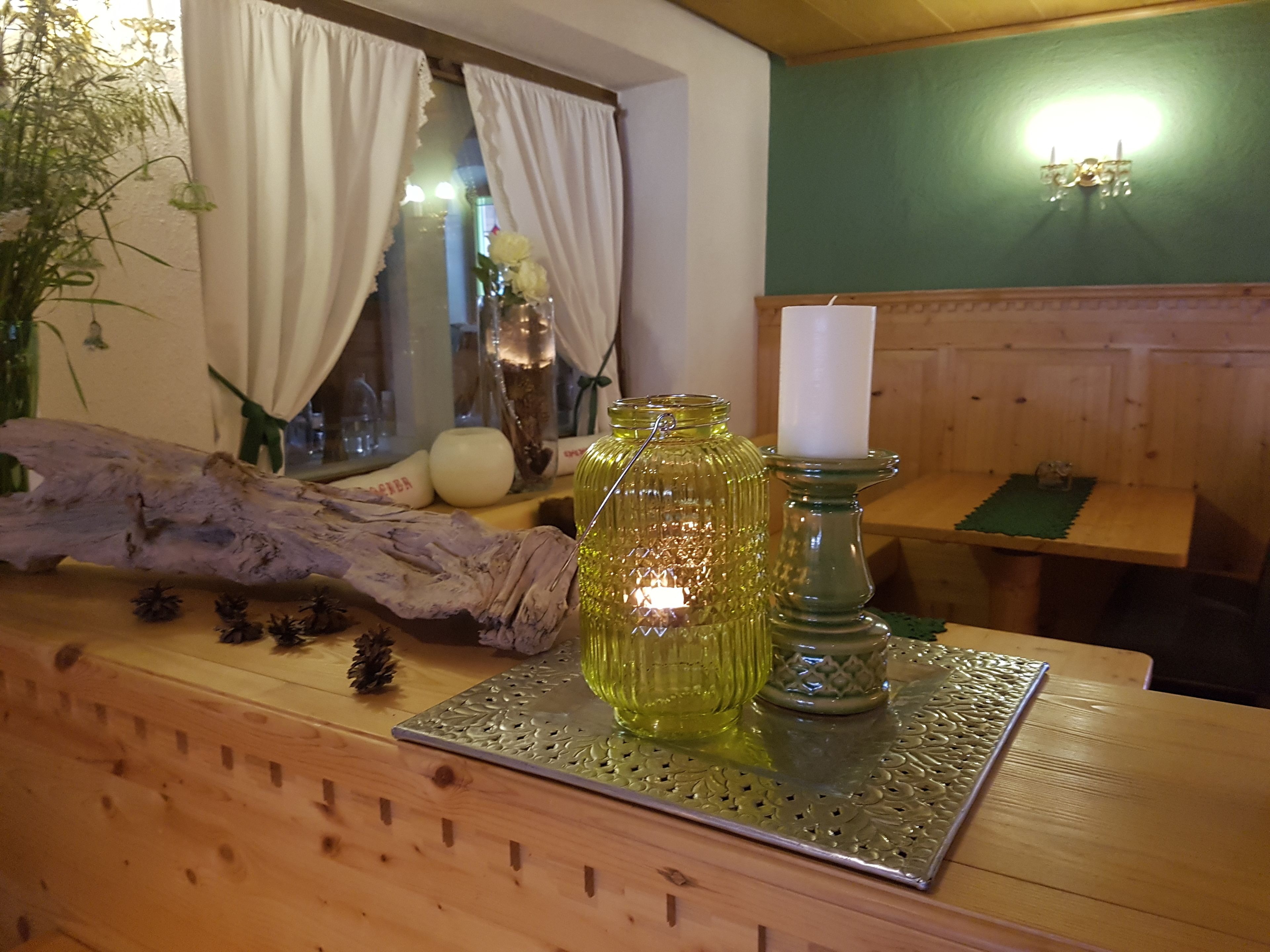 A wooden reception desk with a glass vase, a candle holder, and a decorative pine cone.