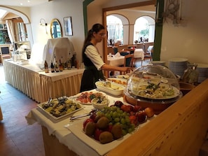A buffet setup with various food items and a server attending to it. - Alphotel Stocker (Campo Tures)