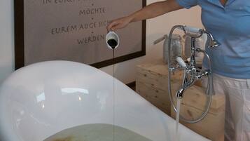 A bathtub with running water, a wooden cabinet, and a wall with text in German.
