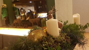 A table with a decorative centerpiece featuring a candle, a golden ornament, and green foliage.