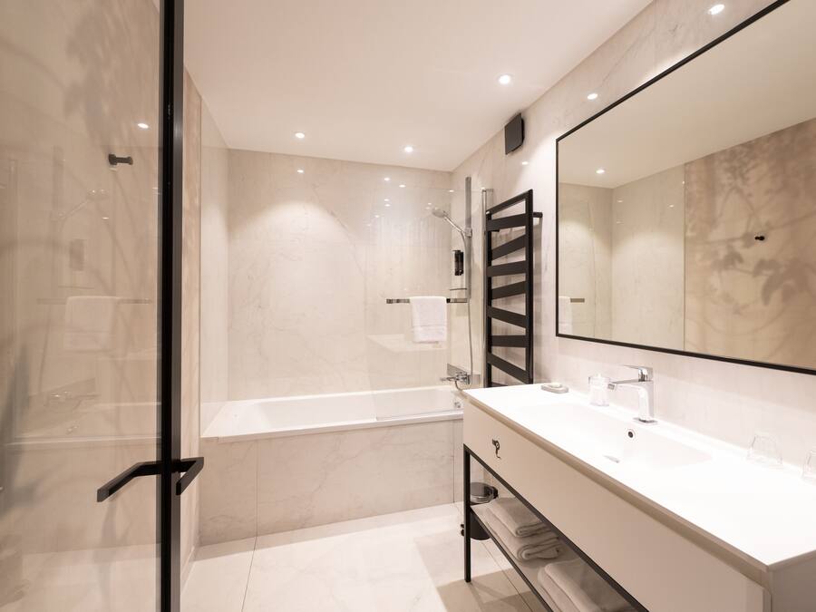 A modern bathroom with a glass shower enclosure, a white bathtub, and a vanity with a large mirror.