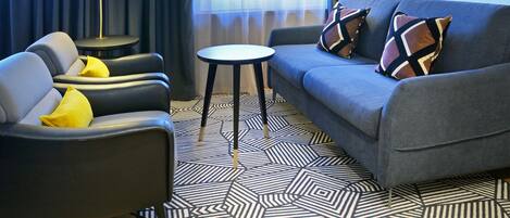 Una sala de estar moderna con un sofá gris, una mesita redonda y una lámpara de pie.
