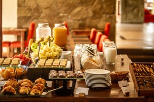 Un bufé con diferentes opciones de comida, incluyendo frutas, pastelería y postres.