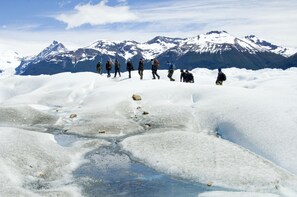 A group of people walking on a snow-covered path with mountains in the background. - Sent Calafate (El Calafate)