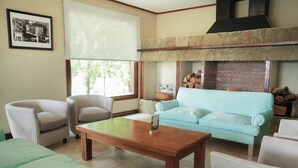 A living room with a fireplace, a sofa, a coffee table, and a chair. - Sent Calafate (El Calafate)