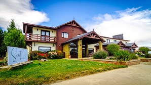 A hotel with a red and beige exterior, a balcony, and a sign indicating it is the "Hotel El Calafate." - Sent Calafate (El Calafate)