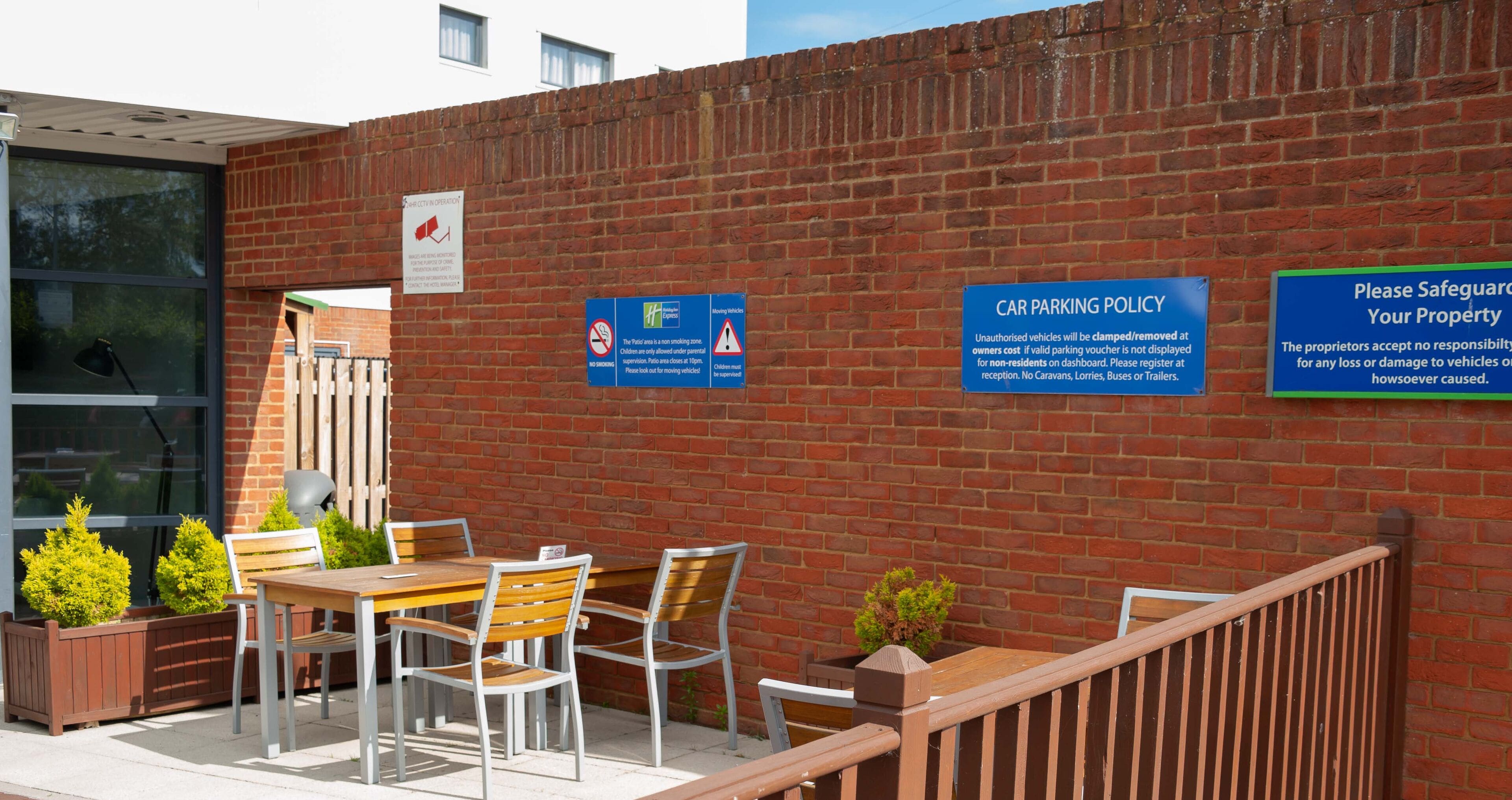 An outdoor seating area with a brick wall, a table, chairs, and potted plants.