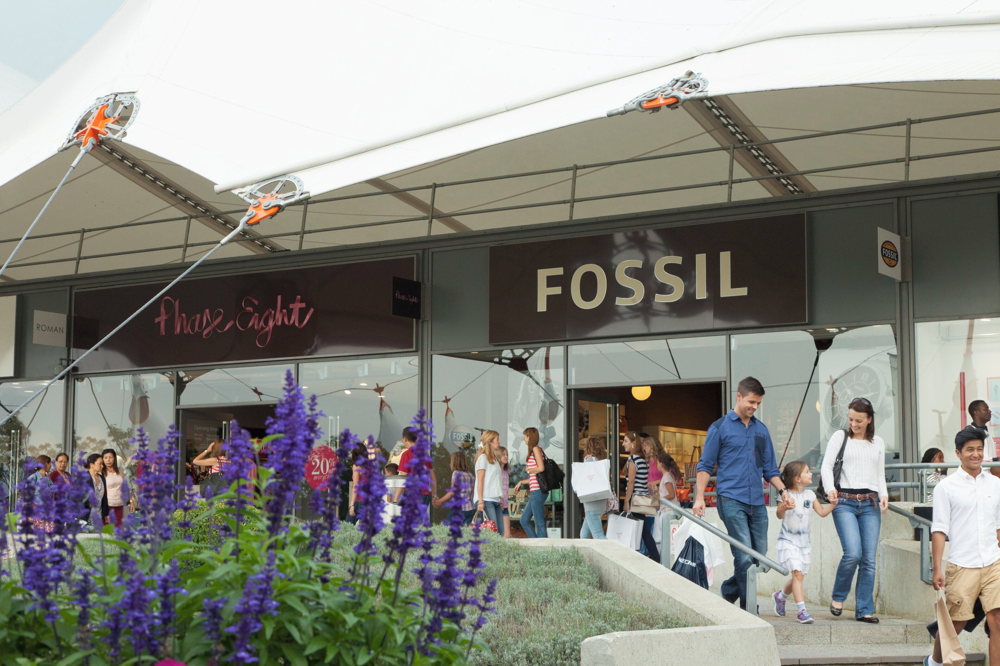 Ein modernes Gebäude mit einem Schild, auf dem 'FOSSIL' und ein weiteres Schild für 'Phase Eight' steht.
