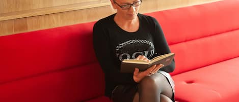 A person sitting on a red bench in a Holiday Inn Express lobby, holding a book.
