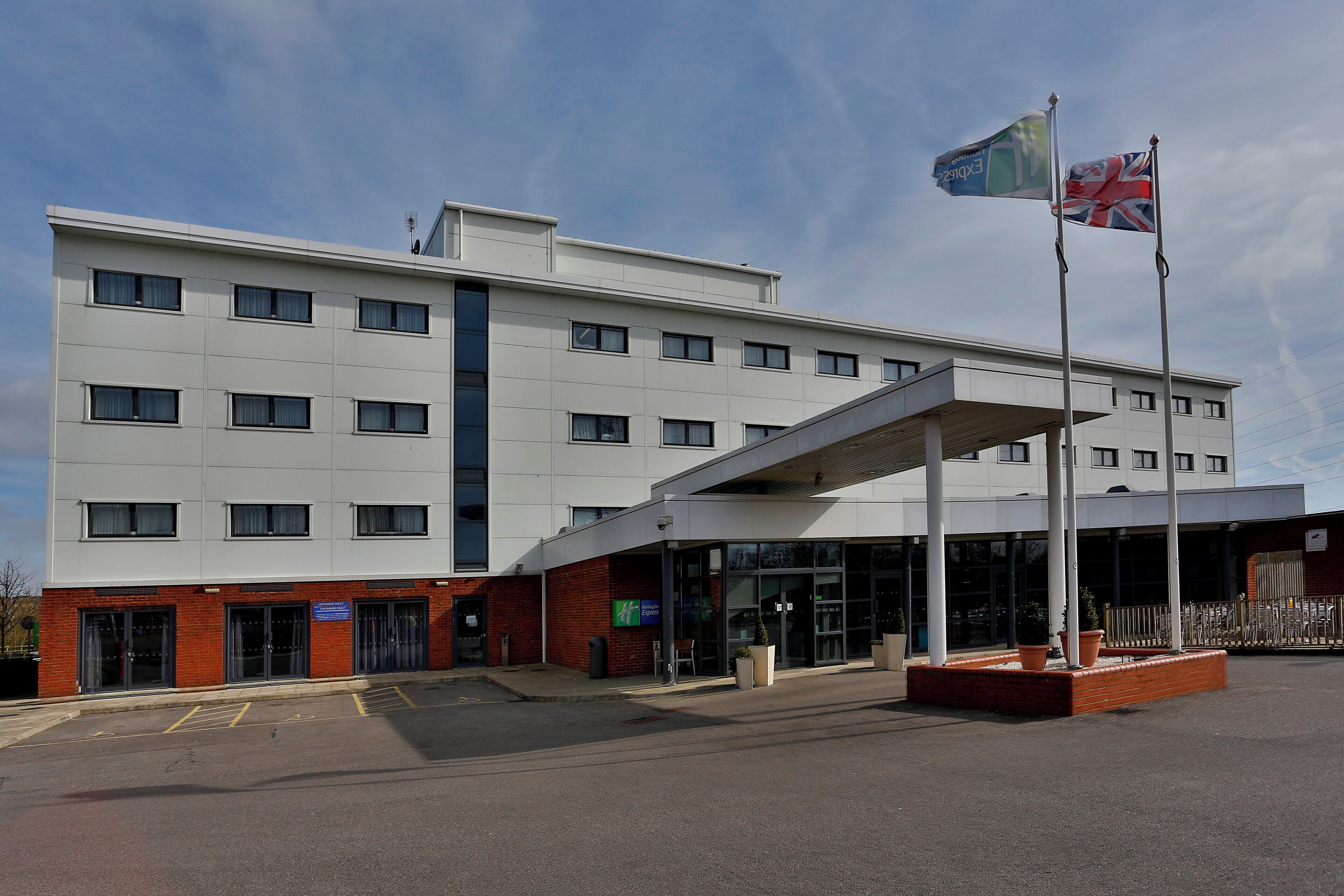 A modern building with a flat facade, multiple windows, and a covered entrance area.