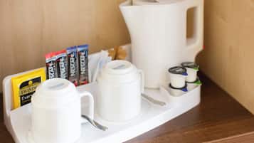 A coffee station with a tray, two cups, a coffee pot, and packets of creamer.