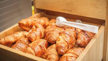 A wooden box filled with croissants and a white measuring spoon.