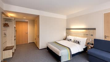 Habitación de hotel con cama, sofá, armario y escritorio con teléfono.