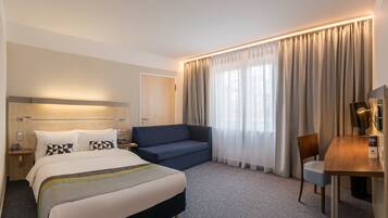 Een hotelkamer met een bed, een bank, een bureau en een stoel.