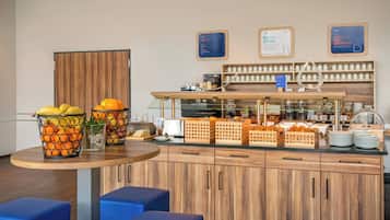 Ein Frühstücksbuffet mit Obstkörben, einer Kaffeemaschine und einer Auswahl an Tassen.