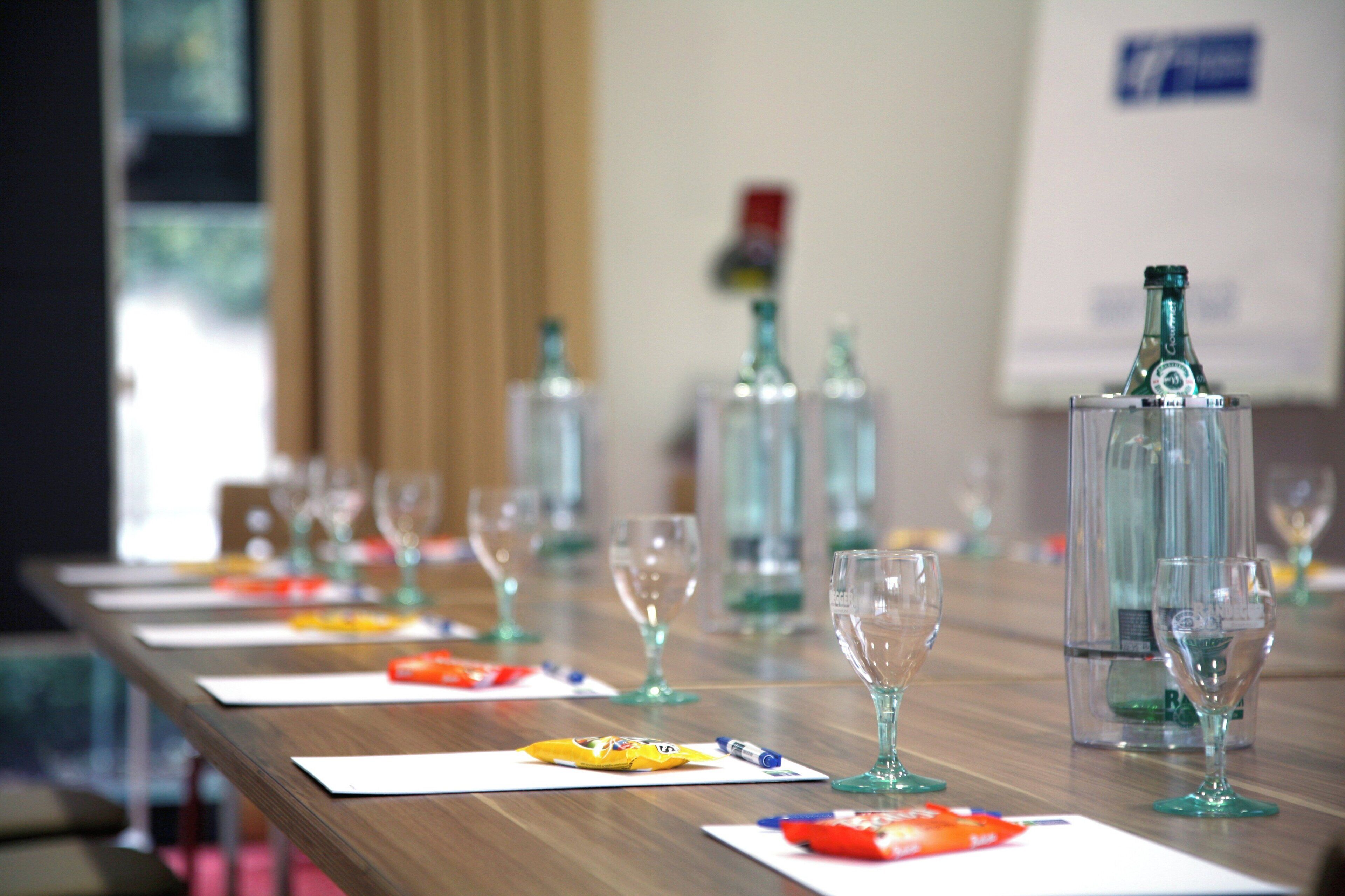 A conference table with multiple wine glasses and bottles, indicating a setting for a meeting or event.