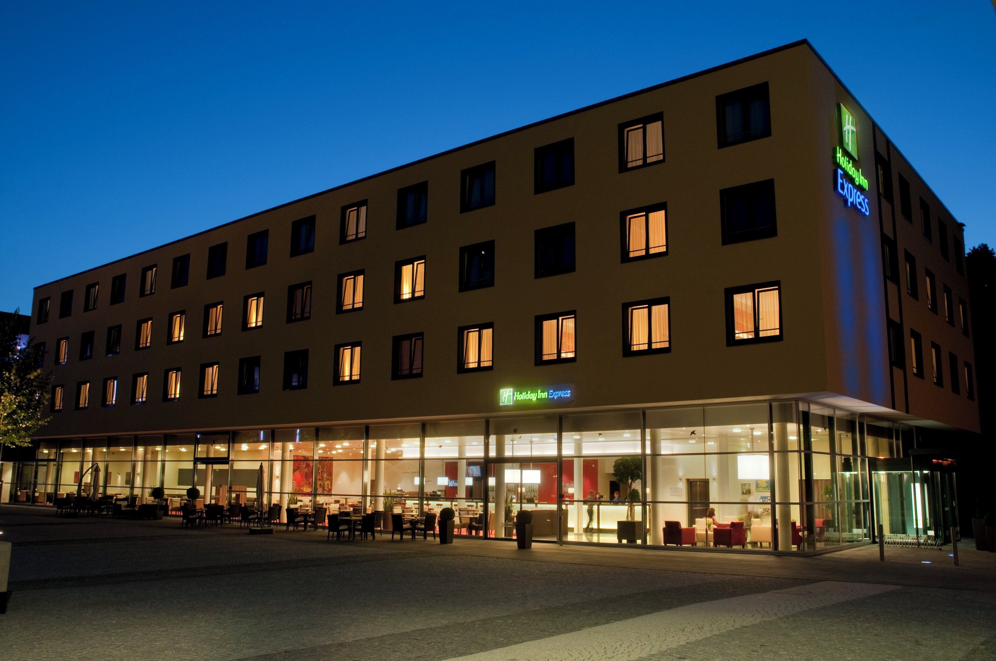 A multi-story hotel with a glass facade, outdoor seating area, and a Holiday Inn Express sign.