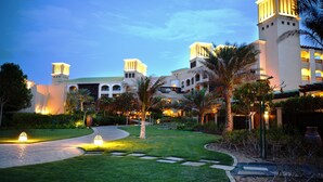 Un resort con un patio central, palmeras y un edificio grande con múltiples torres.