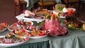 Uma mesa com diversos pratos, incluindo frutos do mar, carnes e legumes, preparada para uma refeição.