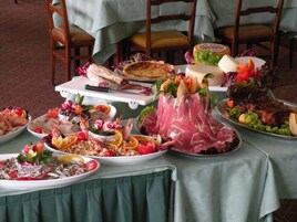 Una mesa con diversos platos, entre ellos mariscos, carnes y verduras, dispuesta para una comida.