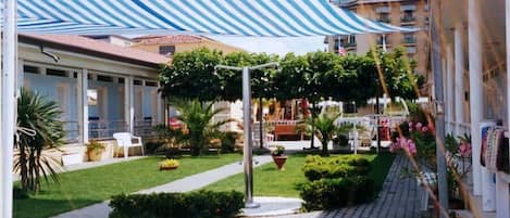 A courtyard with a striped awning, potted plants, and a pathway.