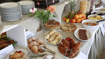 Una mesa de buffet con diversos pasteles, frutas y una variedad de platos.