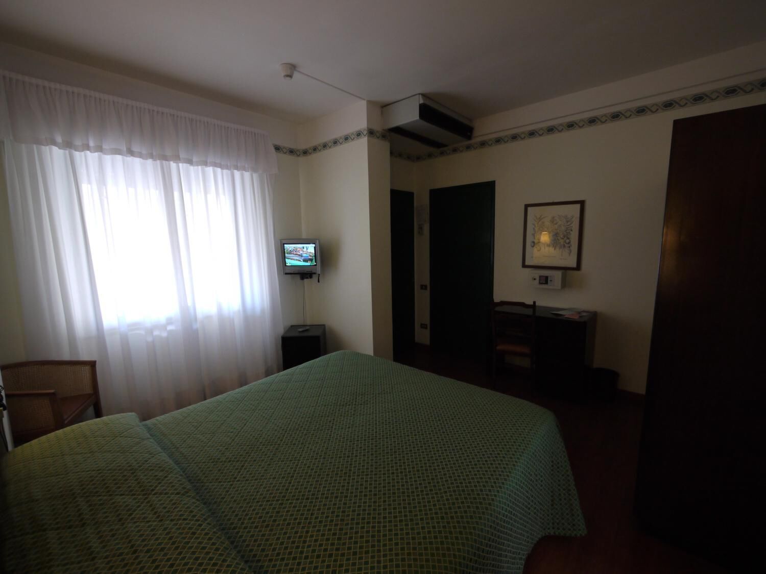 Una habitación de hotel con cama, televisión, escritorio y una silla.