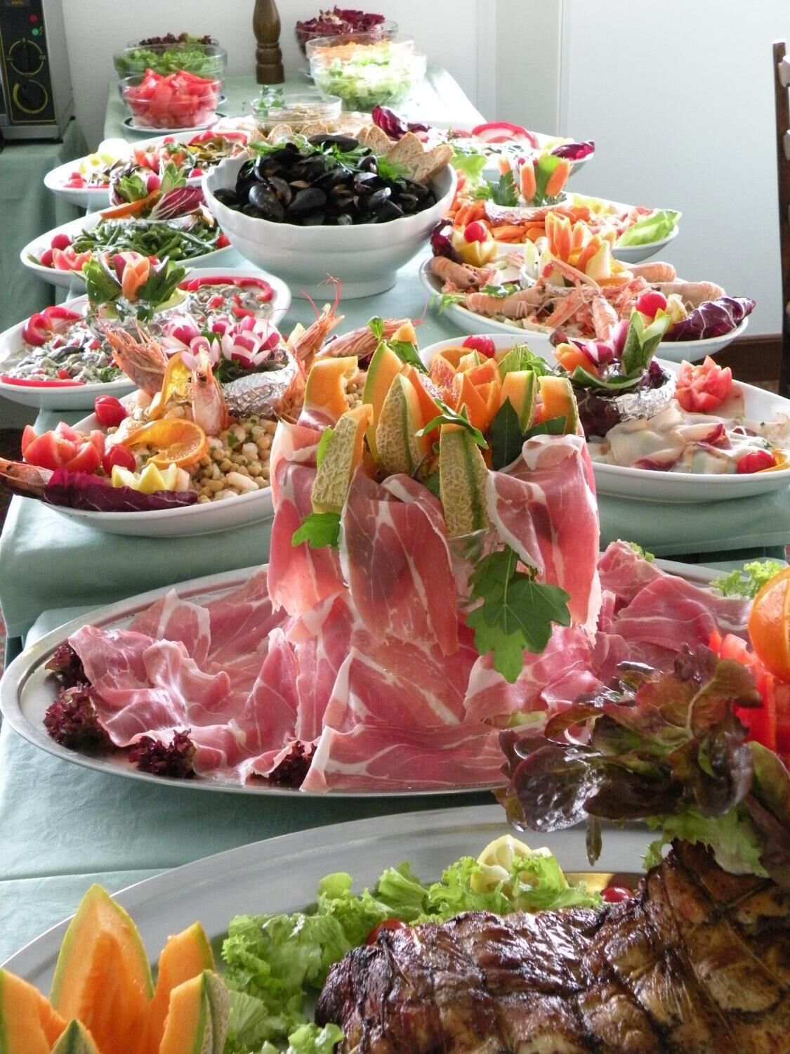 A buffet table with various dishes including meats, salads, and seafood.