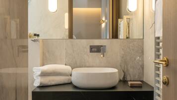 Un baño moderno con tocador de mármol, un espejo grande y un toallero empotrado.
