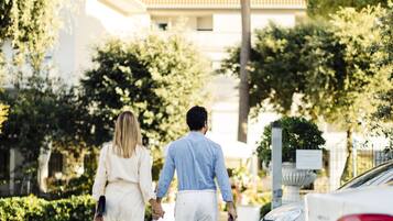 A couple walking on a gravel path with a building in the background.