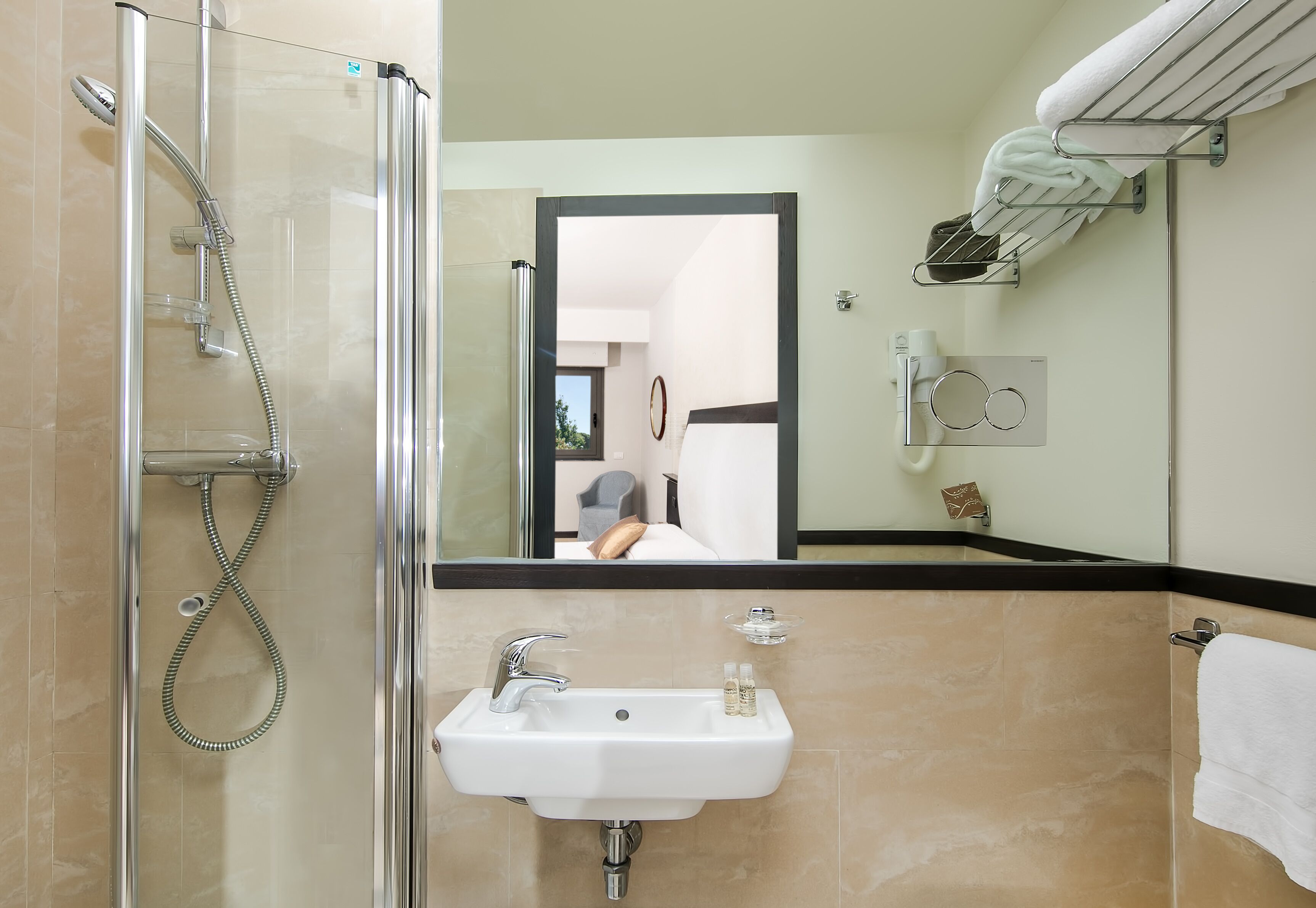 Un baño moderno con ducha envuelta en vidrio, un lavabo con espejo y un perchero para toallas.