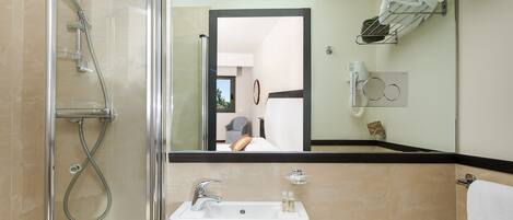 Un baño moderno con ducha envuelta en vidrio, un lavabo con espejo y un perchero para toallas.