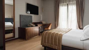 Ein Hotelzimmer mit Bett, Schreibtisch, Stuhl, Fernseher und einem großen Spiegel.