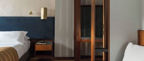 A hotel room with a bed, a nightstand, a wooden wardrobe, and a seating area.