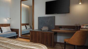 Una habitación de hotel con cama, escritorio, silla, televisor y un espejo grande.