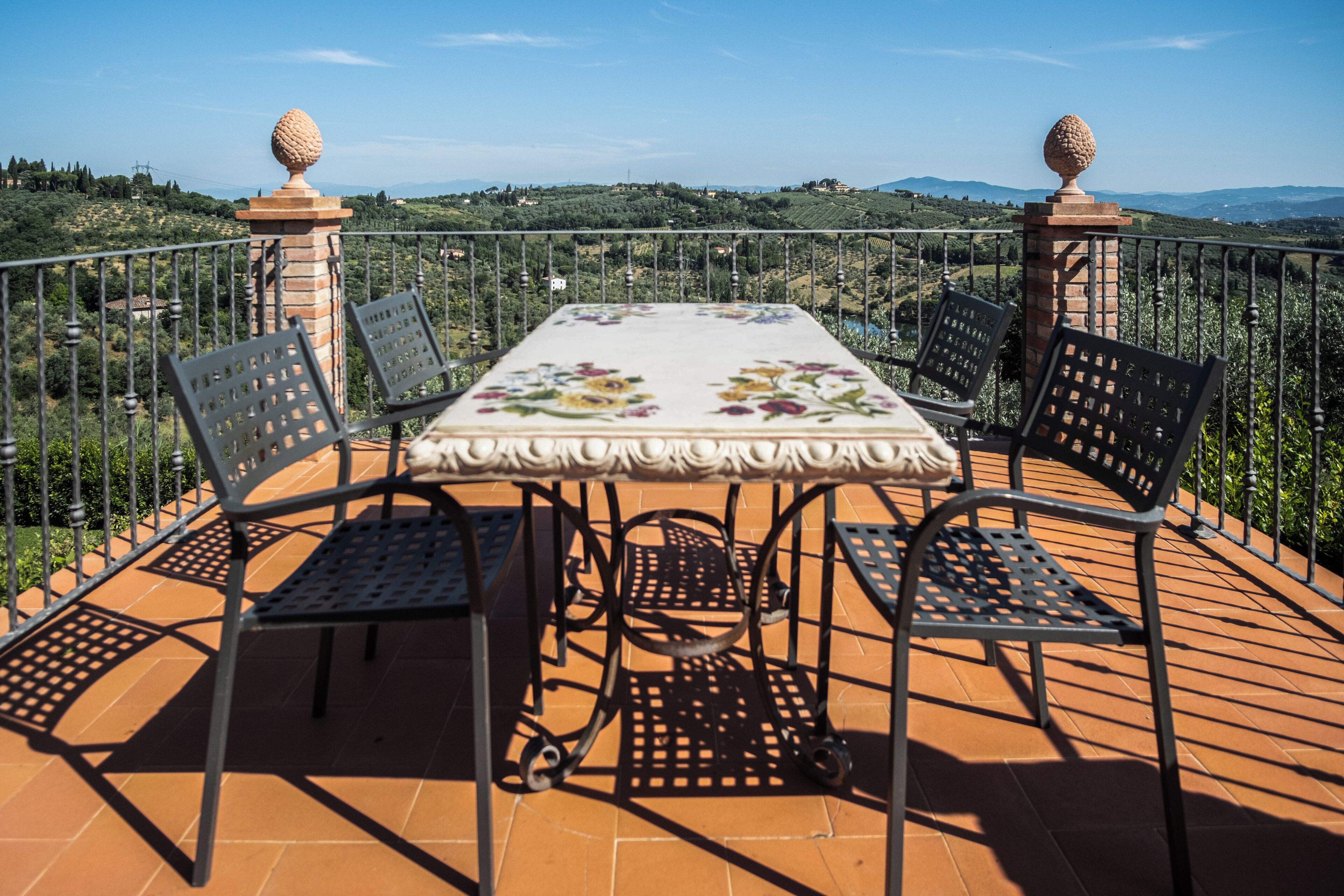 Une terrasse avec une table et des chaises, une vue sur la campagne et une balustrade.