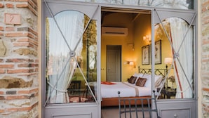 A room with a bed, bedside table, lamp, and a window with curtains.