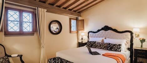 A bedroom with a bed, a chair, a nightstand, a lamp, and a window with curtains.