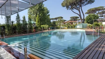 Una piscina al aire libre, sombrillas, sillones reclinables de piscina