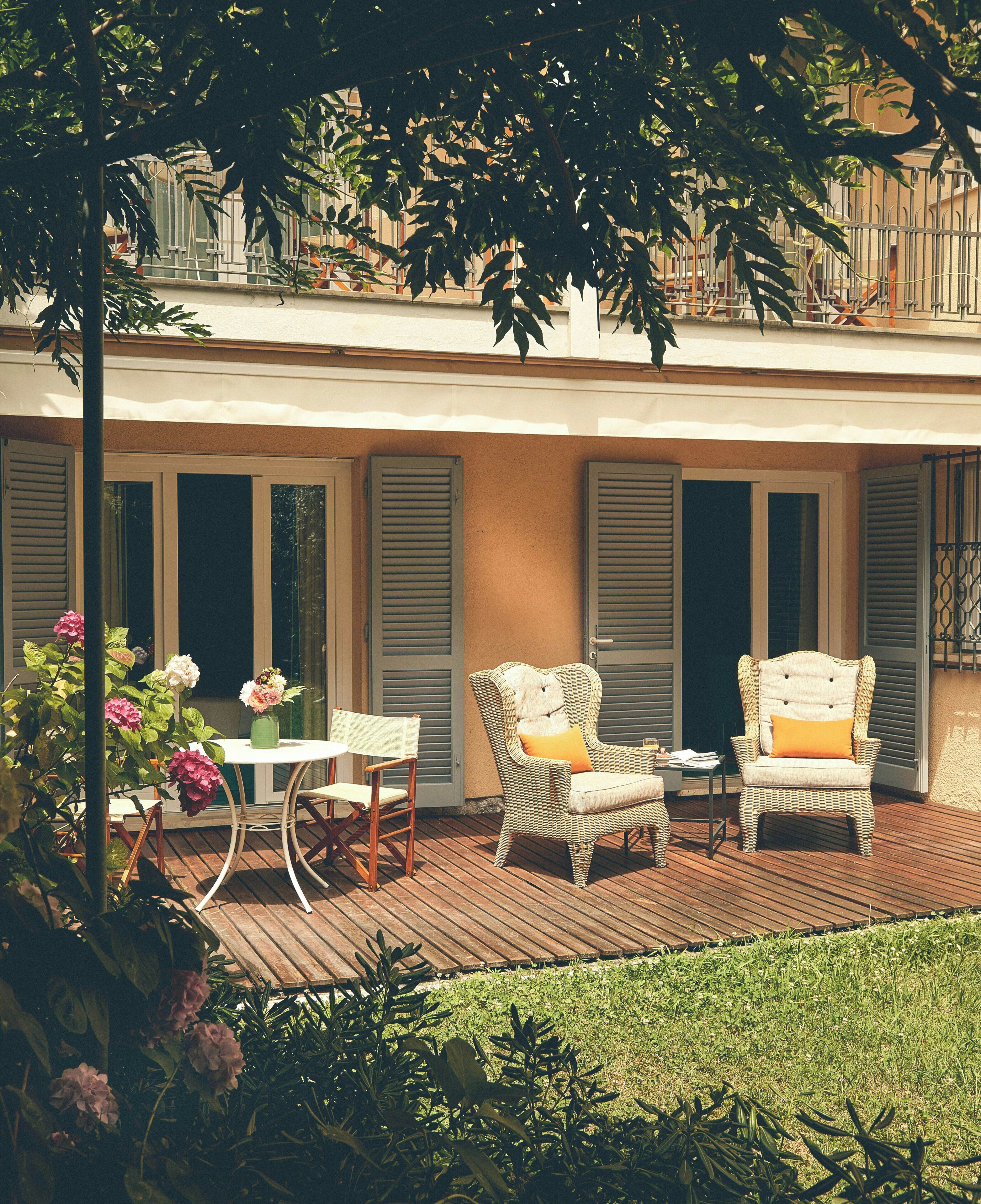 Un patio con sedie in vimini, un tavolo e un vaso di fiori.