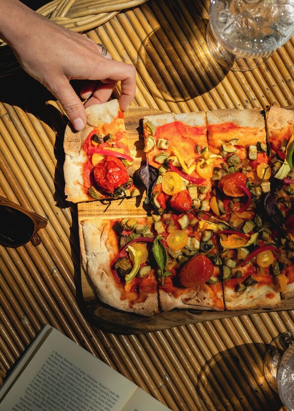Pizza con varios vegetales sobre una mesa de madera.