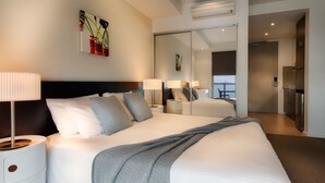 Un moderno cuarto de hotel con una cama grande, lámparas de noche, un televisor de pantalla plana y vistas a la ciudad.