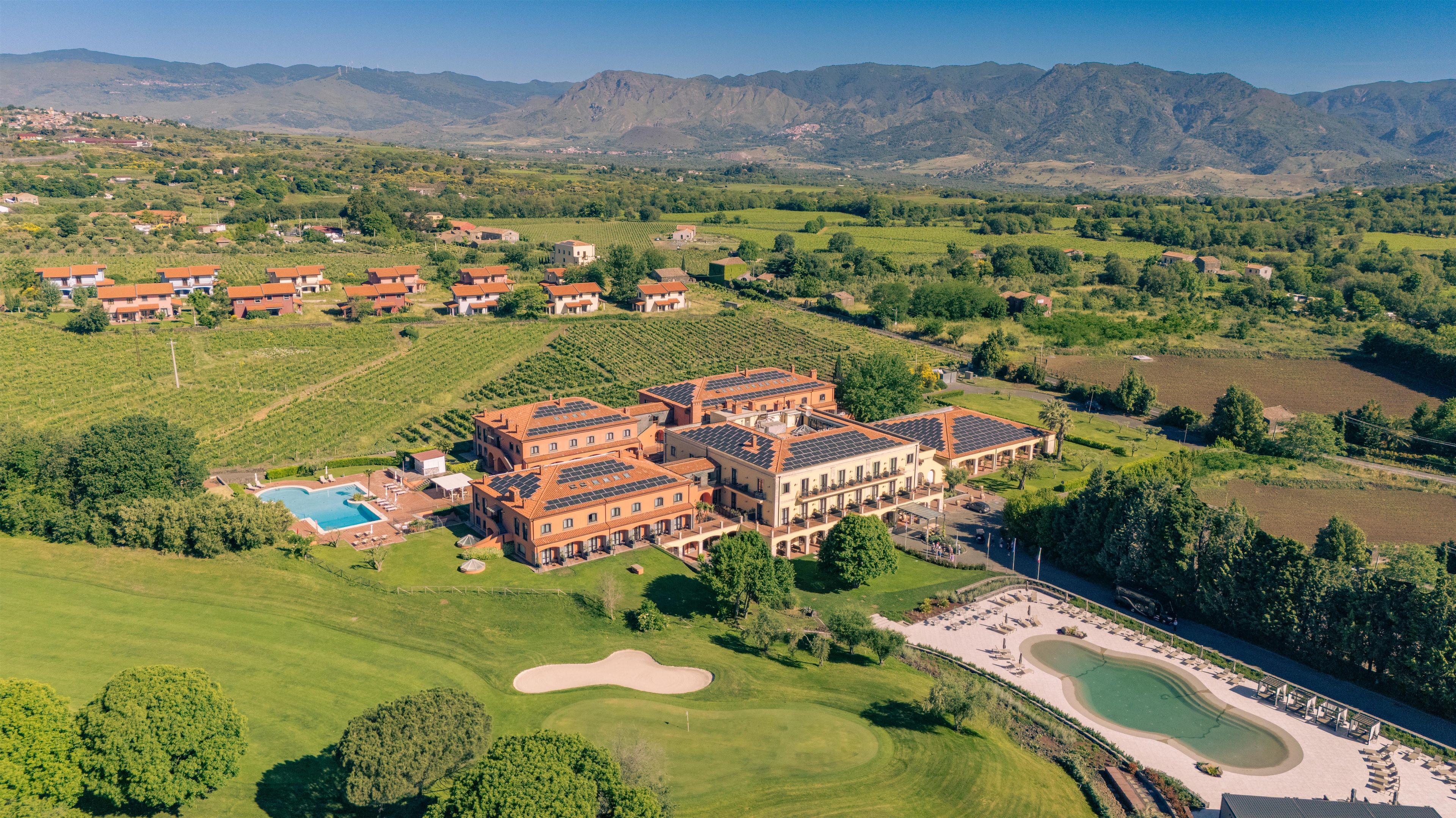 Un'ampia tenuta con diversi edifici, una piscina e un campo da golf.