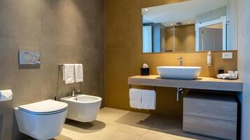 Une salle de bain moderne équipée de toilettes, d’un bidet et d’un grand lavabo avec un miroir au-dessus.
