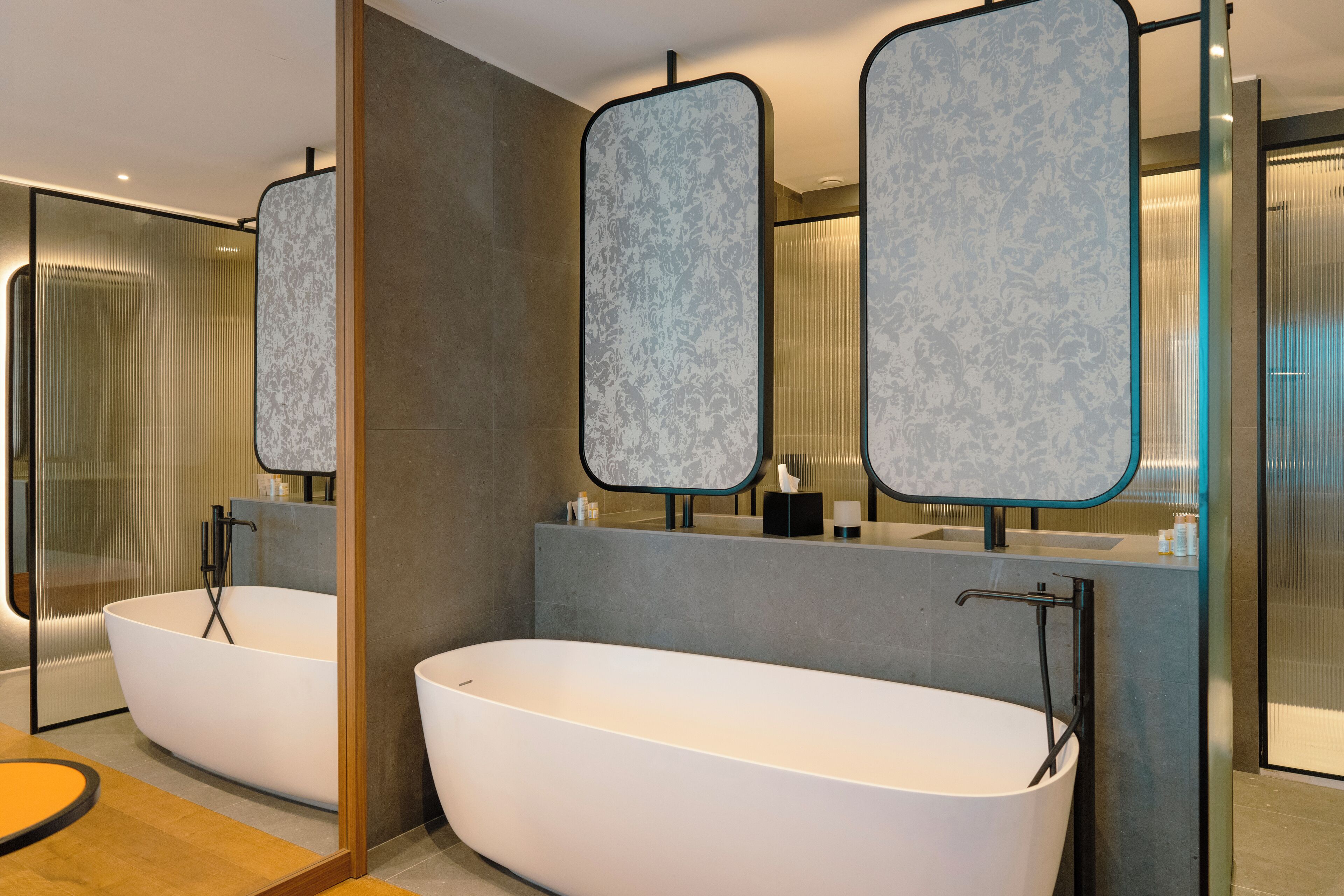 Un bagno moderno con due vasche da bagno indipendenti, uno specchio grande e un box doccia in vetro.