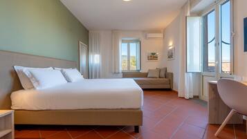 Ein modernes Hotelzimmer mit einem großen Bett, einer Sitzecke, einem Schreibtisch und Blick ins Freie.