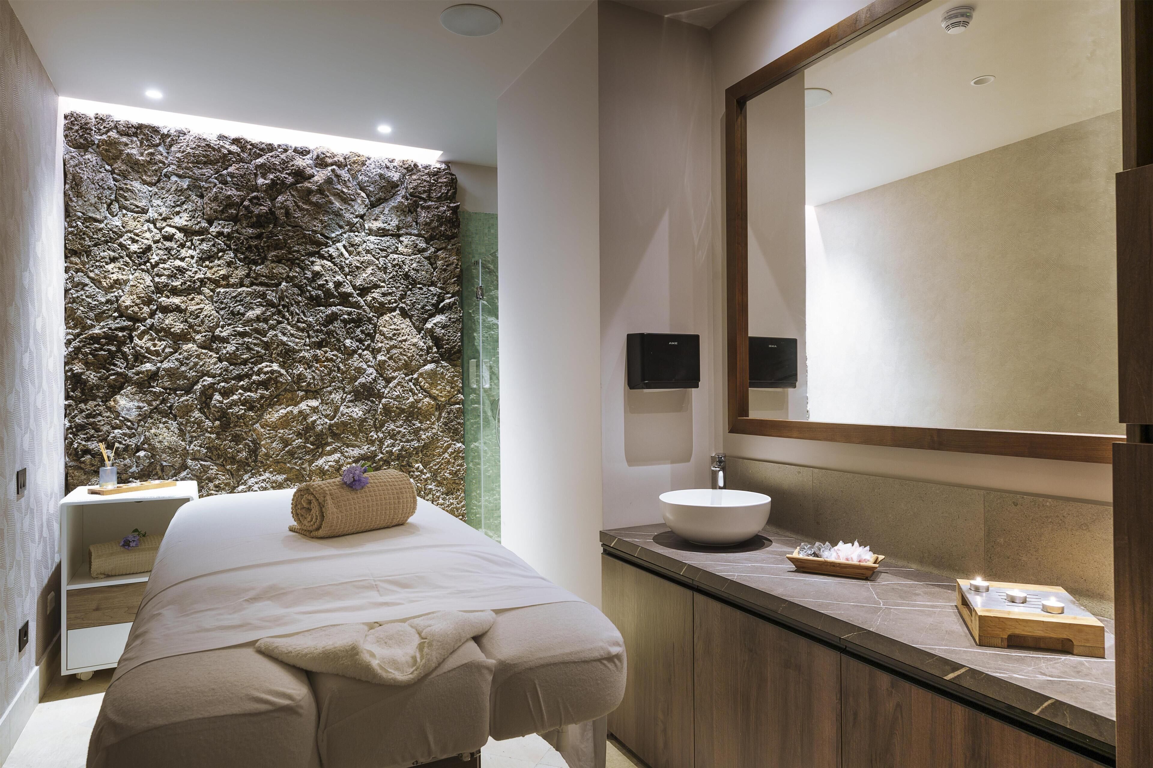 Un bagno moderno con parete in pietra, un letto, un lavandino e uno specchio.