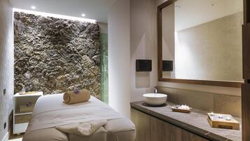 Un bagno moderno con parete in pietra, un letto, un lavandino e uno specchio.